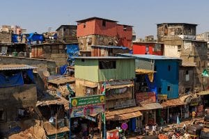 A slum near a train station in Mumbai with precariously stacked buildings packed closely together.