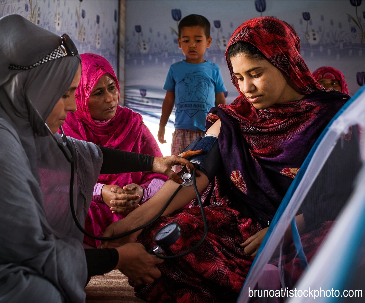 An Algerian woman measures the blood pressure of a woman who has recently given birth.
