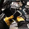 A worker holding cell phones and other electronics, e-waste ready to be recycled.