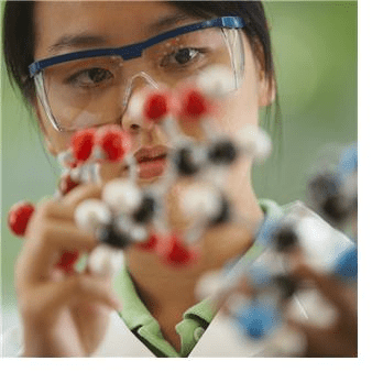 A woman in a lab coat and safety goggles examines a scientific object