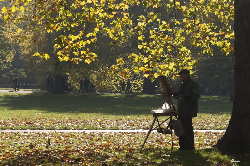 Elderly man painting on easel in park