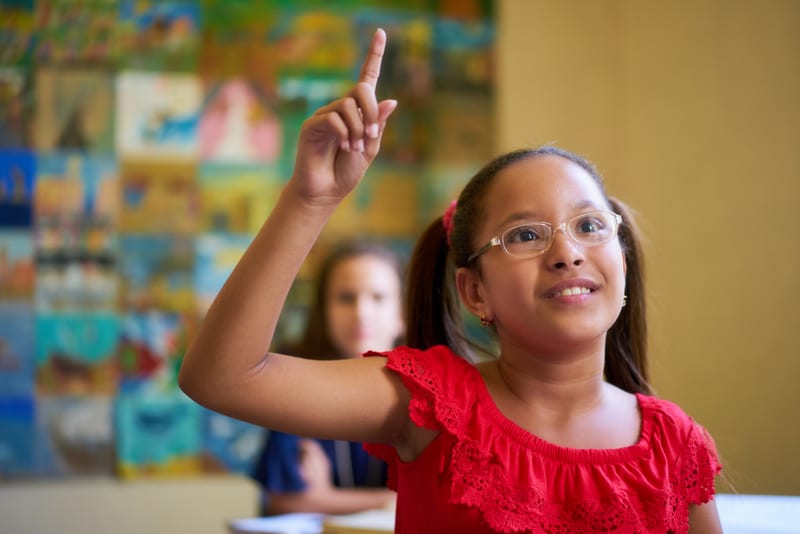 Elementary student raises hand and waits her turn to speak