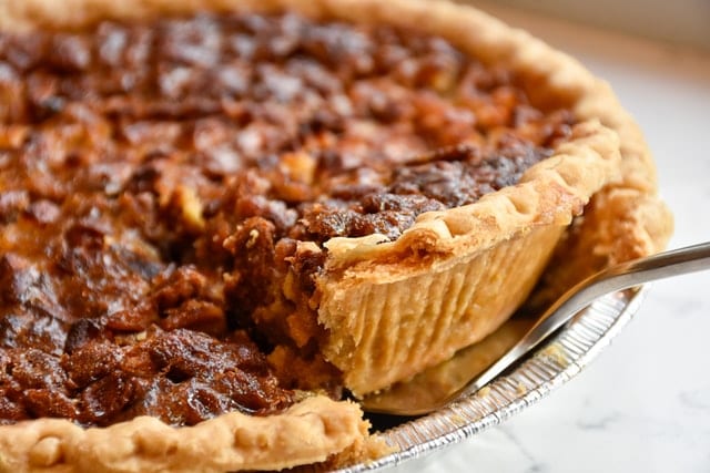 Close up view of a slice of pumpkin pie being removed by a fork