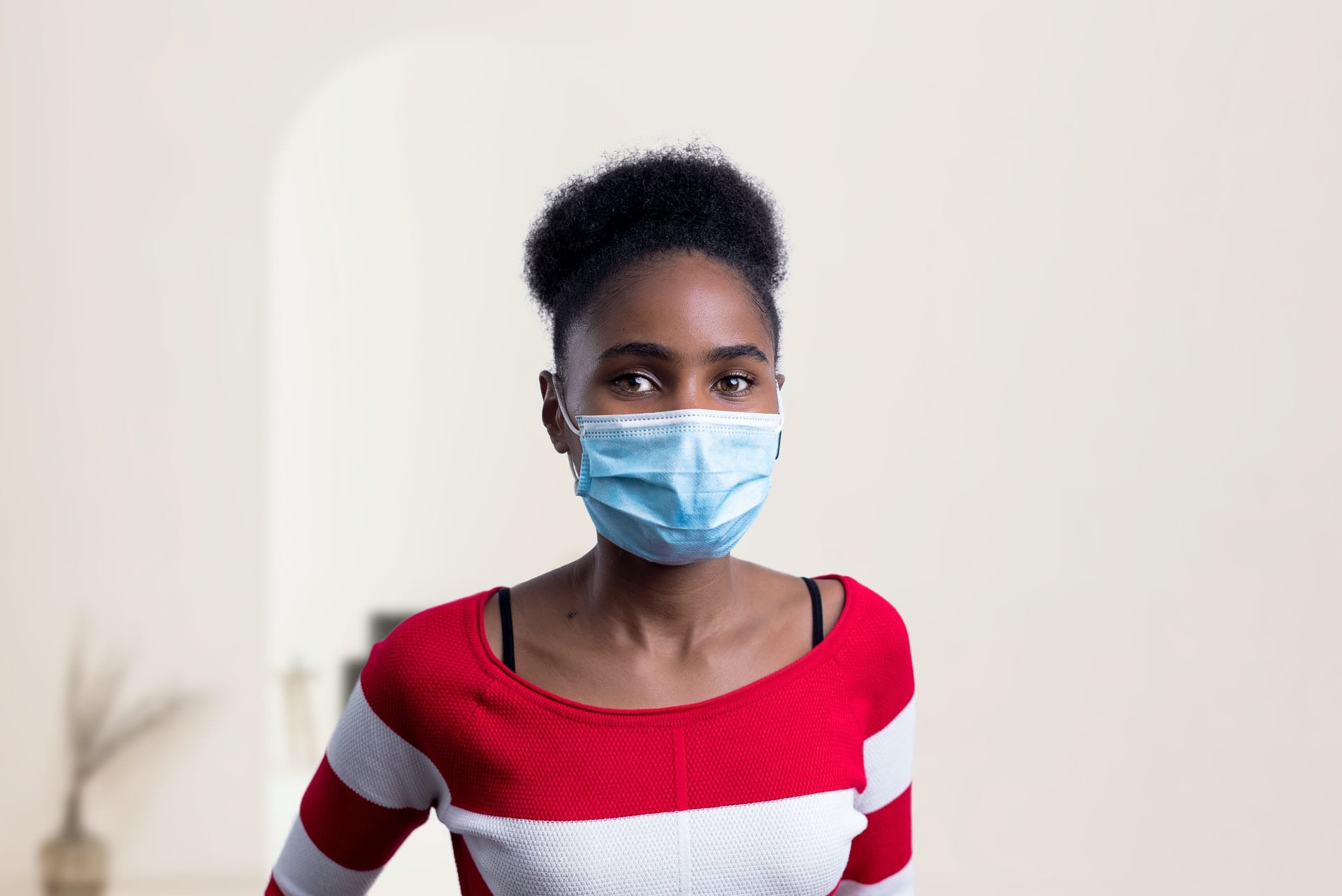 Woman in red and white striped sweater poses in blue single use face mask