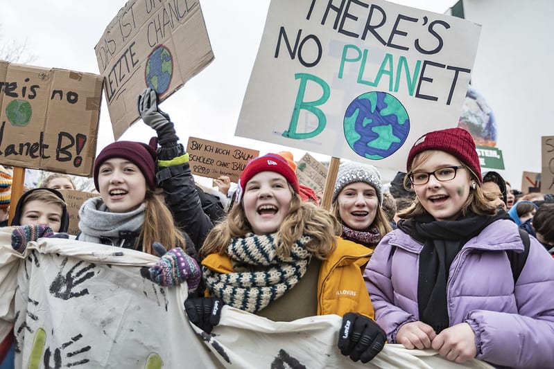 Students smile and hold banners and signs at a climate protest