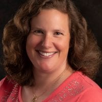 Kate Silvis headshot, smiling, black background