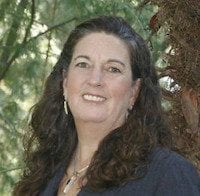 Lynda Deschambault headshot, smiling, trees in background