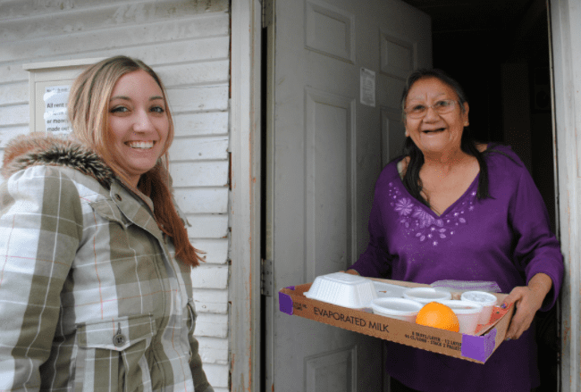 Two women smile while completing Meals on Wheels delivery