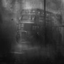 A 1950s black and white photo shows a double decker bus parked on a London street in a cloud of smog.