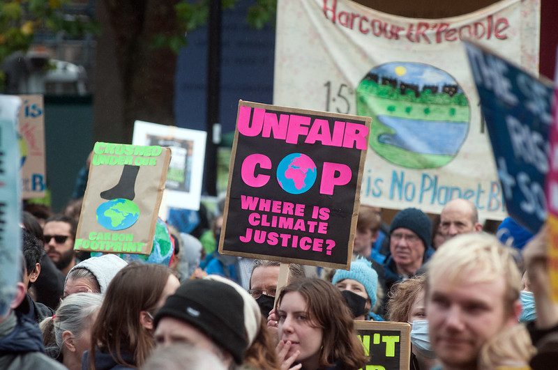 A crowd marches at a climate demonstration, and many individuals hold climate justice signs.