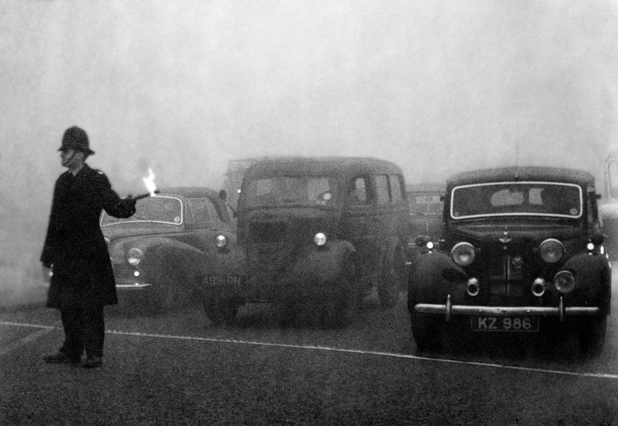 Policeman on point duty seen here using flares to guide the traffic during a heavy smog in London on December 8, 1952
