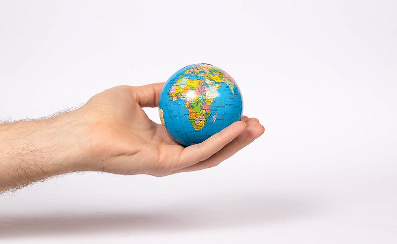 An outstretched arm holds a scale model of planet Earth in its hand