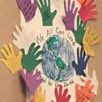 Student project with handprints around an image of Earth
