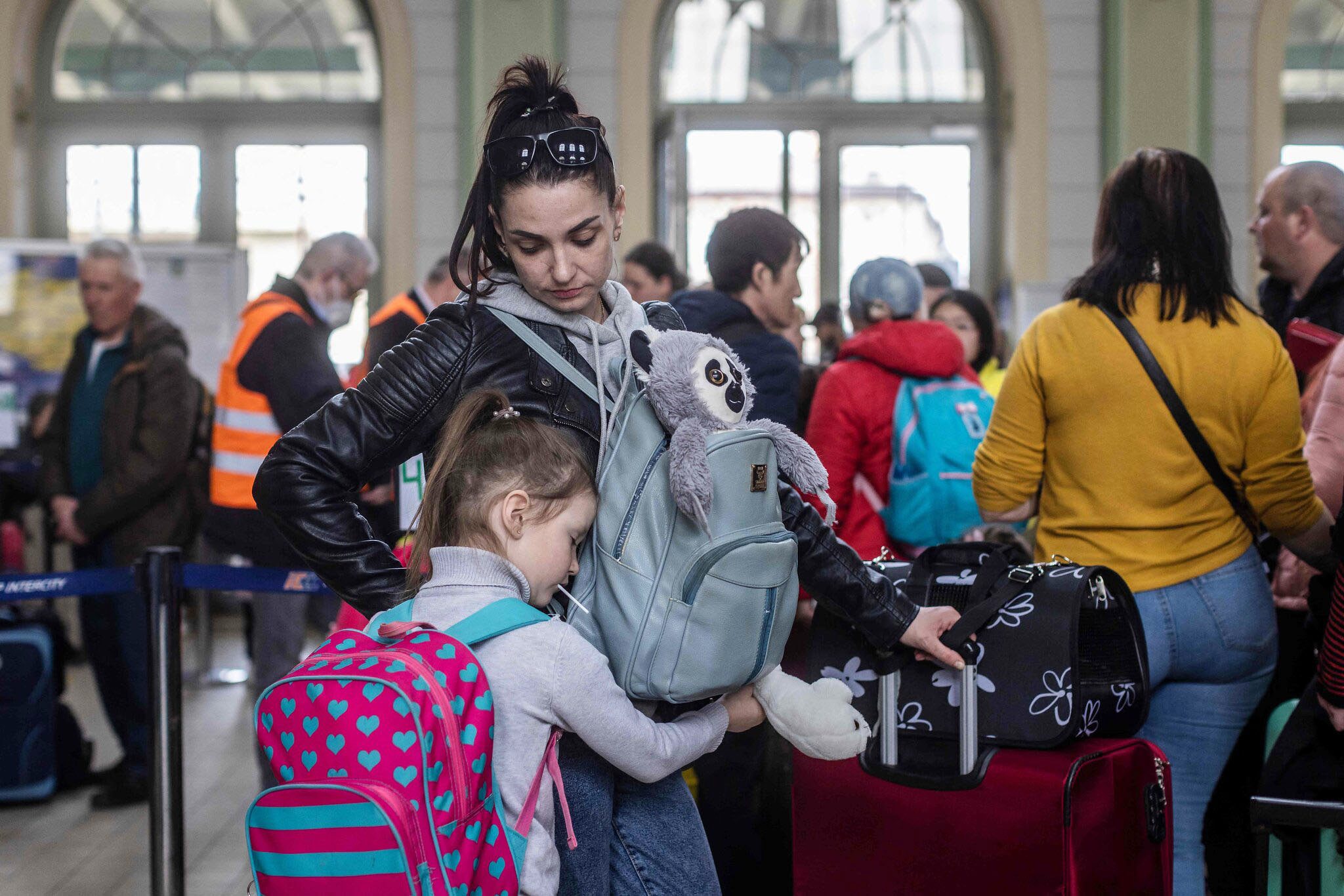 Refugee woman and her daughter with their bags at the train station.