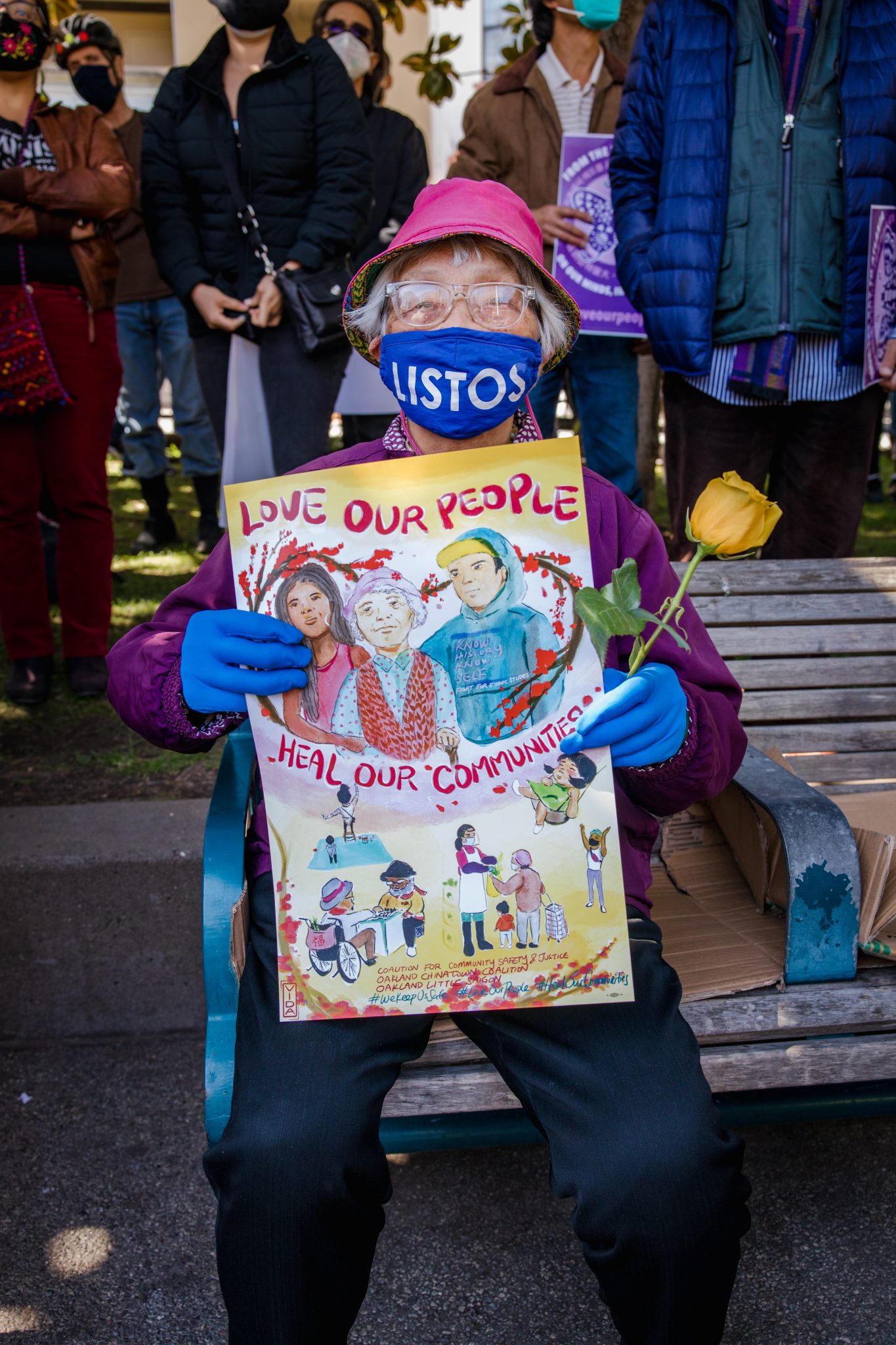 Asian American woman holding a "Love Our People / Heal Our Communities" sign.