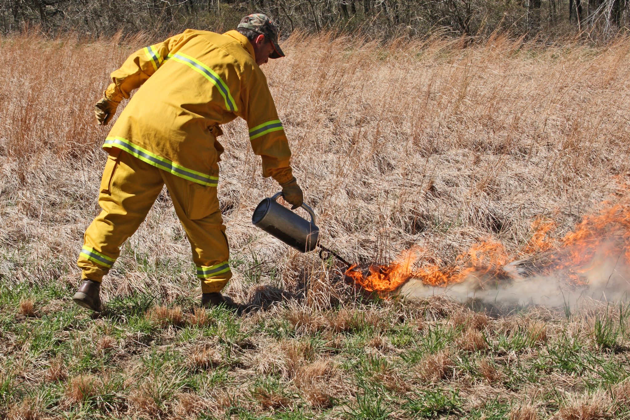 Firefighter performs a controlled burn using a burn pot filled with diesel fuel and gasoline to start the fires