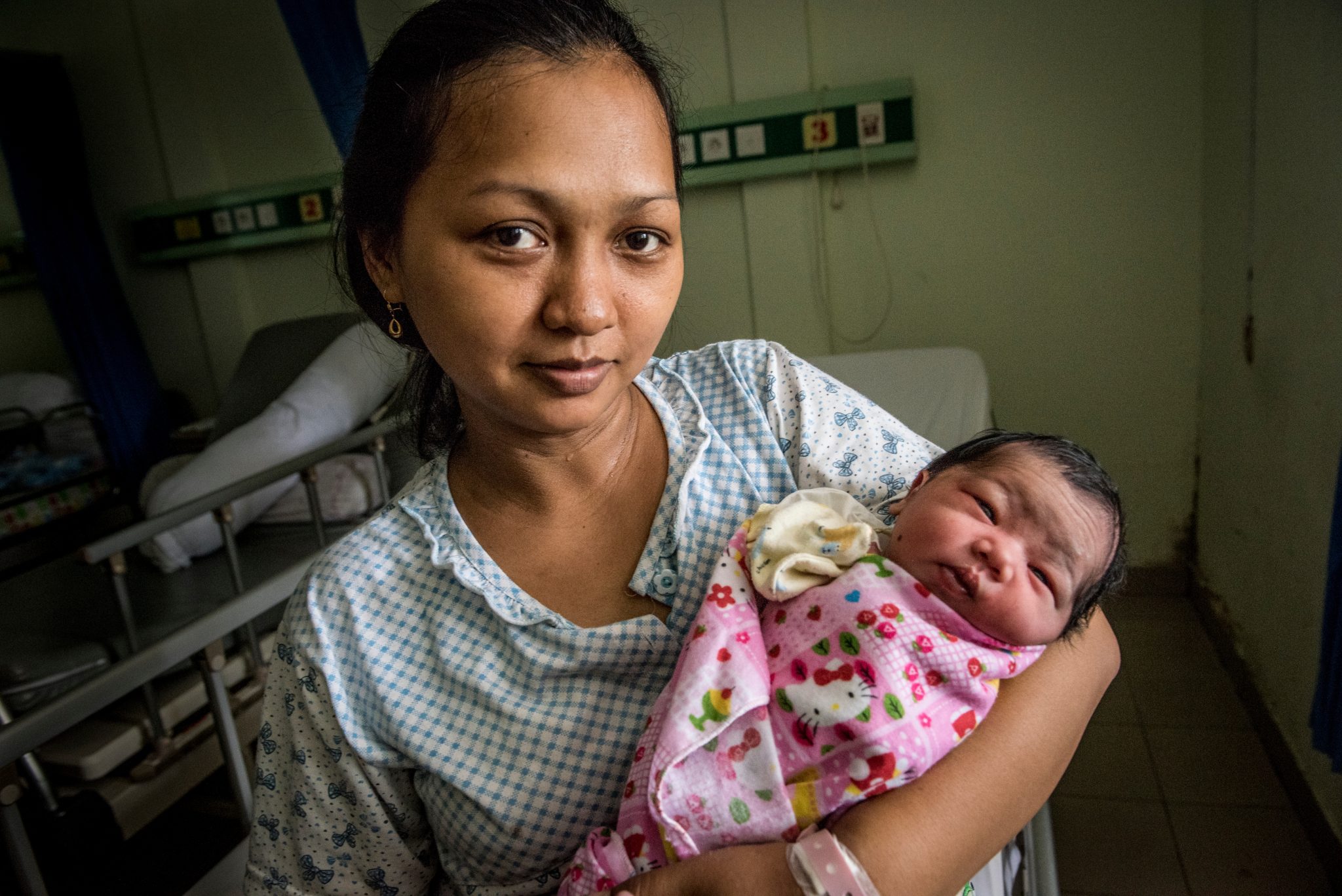 Indonesian mother holding her newborn girl in a hospital.
