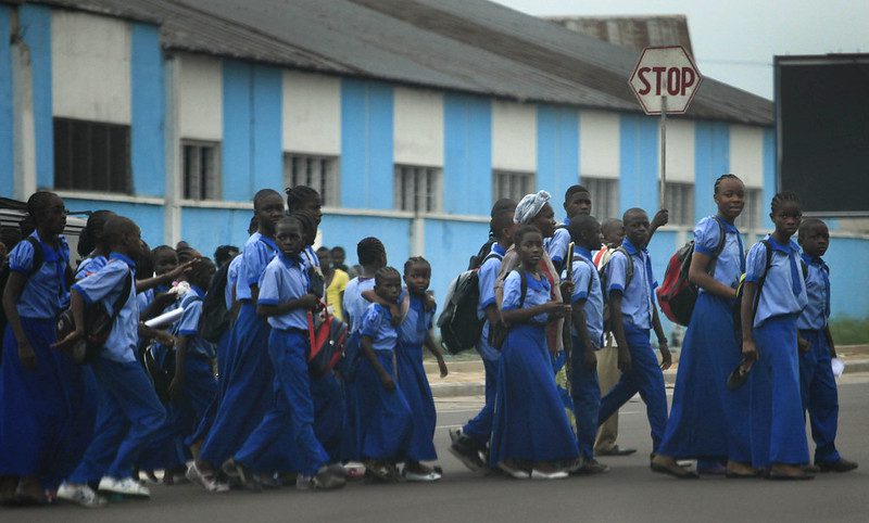 A large group of school children cross the street in Kinshasa, the sixth most densely populated city in the world where over 50% of the population is under 22 years old.