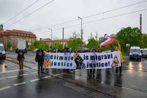 Climate protestors in Germany hold a banner that says “Climate justice is migrant justice!”
