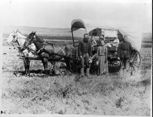 A family from the Great Western Migration poses with their covered wagon in Nebraska, 1886.