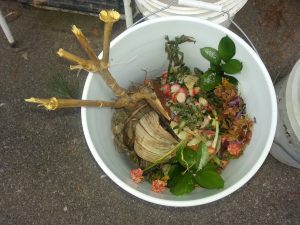 An example of a colorful composting bucket with food scraps and flowers.