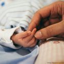 Mother's hand holding the hand of her newborn baby