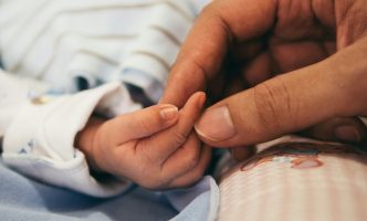 Mother's hand holding the hand of her newborn baby