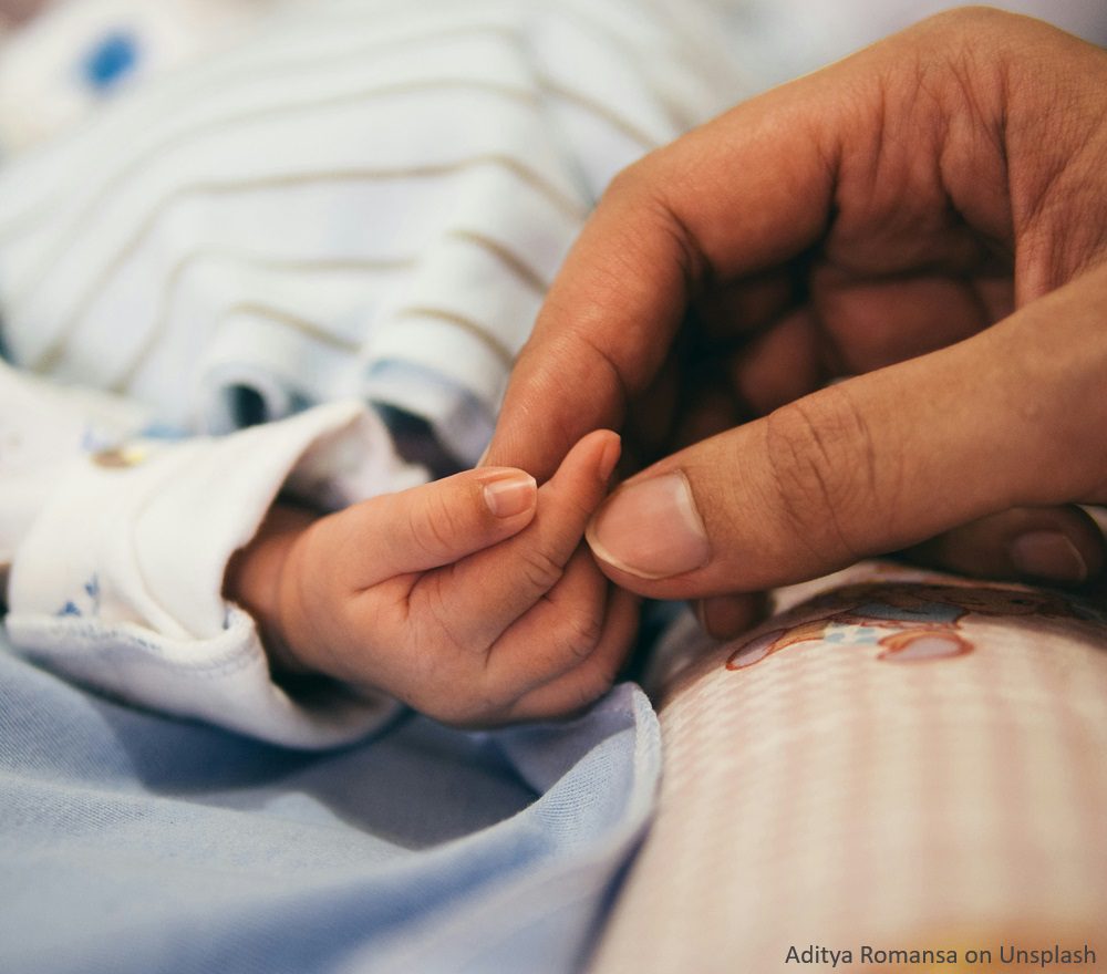 Mother's hand holding the hand of her newborn baby