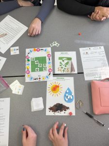 An overhead shot of students playing the K-5 Lessons from the Lorax board game with the game board, playing cards, and resource page.