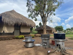 Three energy efficient stoves sit outside in a Ugandan refugee camp. These stoves address both energy poverty and the gendered health consequences of cooking with biomass.
