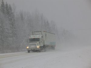 A semi-truck sets out on a snowy highway in Canada, a country with high per capita energy use due to extreme climate and dispersed population.
