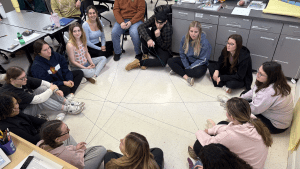 Students in a circle hold connecting yarn as they go through the activity Web of Life to learn about cause and effect within a habitat.