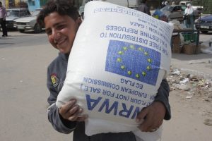 A young Palestinian refugee carries flour distributed by UNRWA as part of their food assistance program.