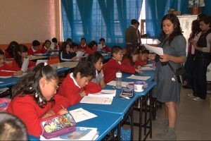A teacher stands in front of rows of students in a classroom in Mexico City.