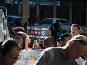 A climate protester holds a sign that says, “Climate change is a health emergency.”