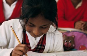 A young student writes on notebook paper in a school in Mexico.