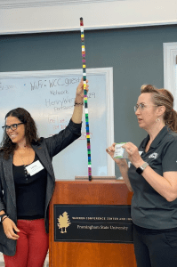 Marni Landry and a partner hold snap cubes to show CO2 emissions as part of the PopEd climate equity activity Carbon Crunch.