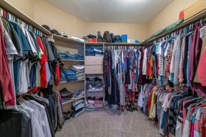A large walk-in closet with hundreds of clothes neatly organized on hangers or folded.