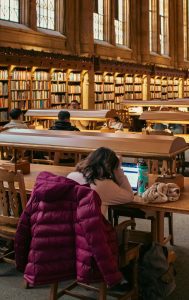 A college student with a laptop studying in a campus library.