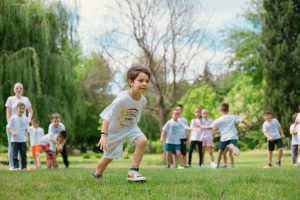 Elementary age students run a relay race outdoors.