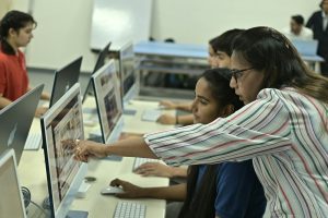 A teacher points to a student's computer screen in a classroom.